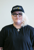 A student faces the camera proudly wearing the RESPECT Snapback: A black snapback hat with the world RESPECT written across the front in large capitol white letters, and a golden "E."